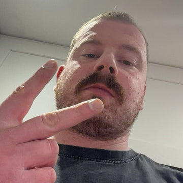 Man making a peace sign with his fingers indoors.